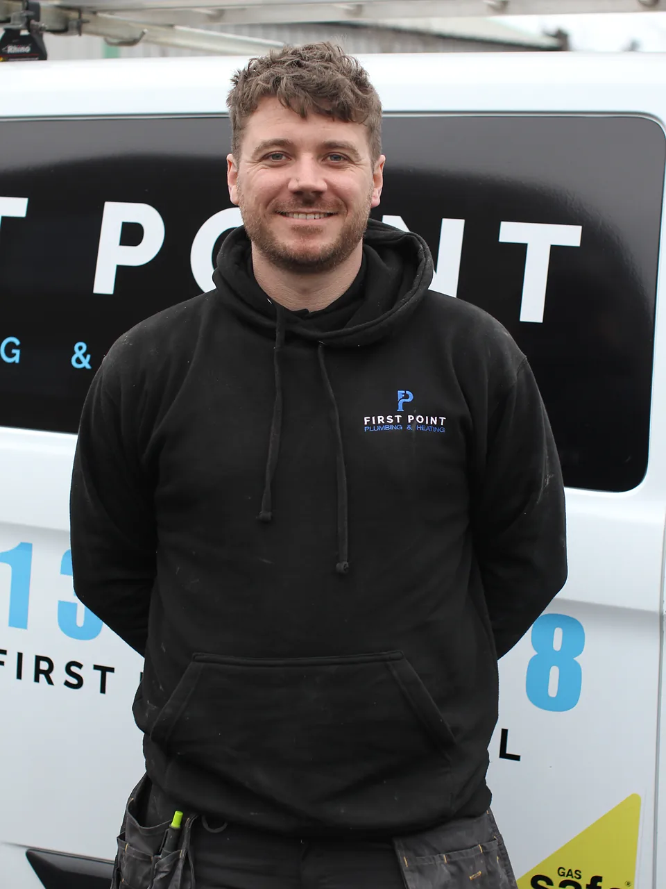 First Point engineer in a black branded hoodie standing in front of the company's white van