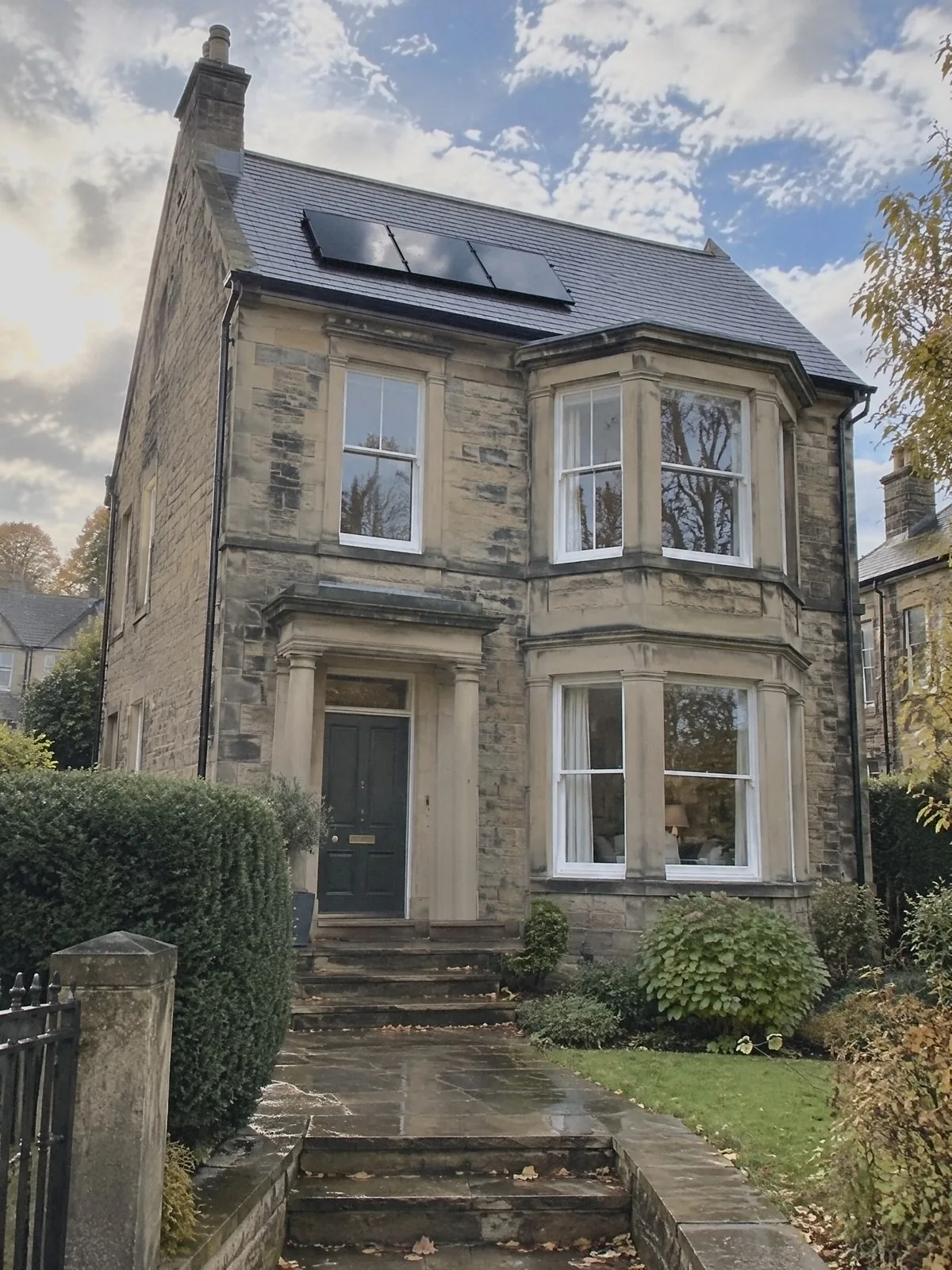 Illustration of a Victorian sandstone detached house after rain, three black solar panels on its slate roof and a wet flagged path and steps up to the front door