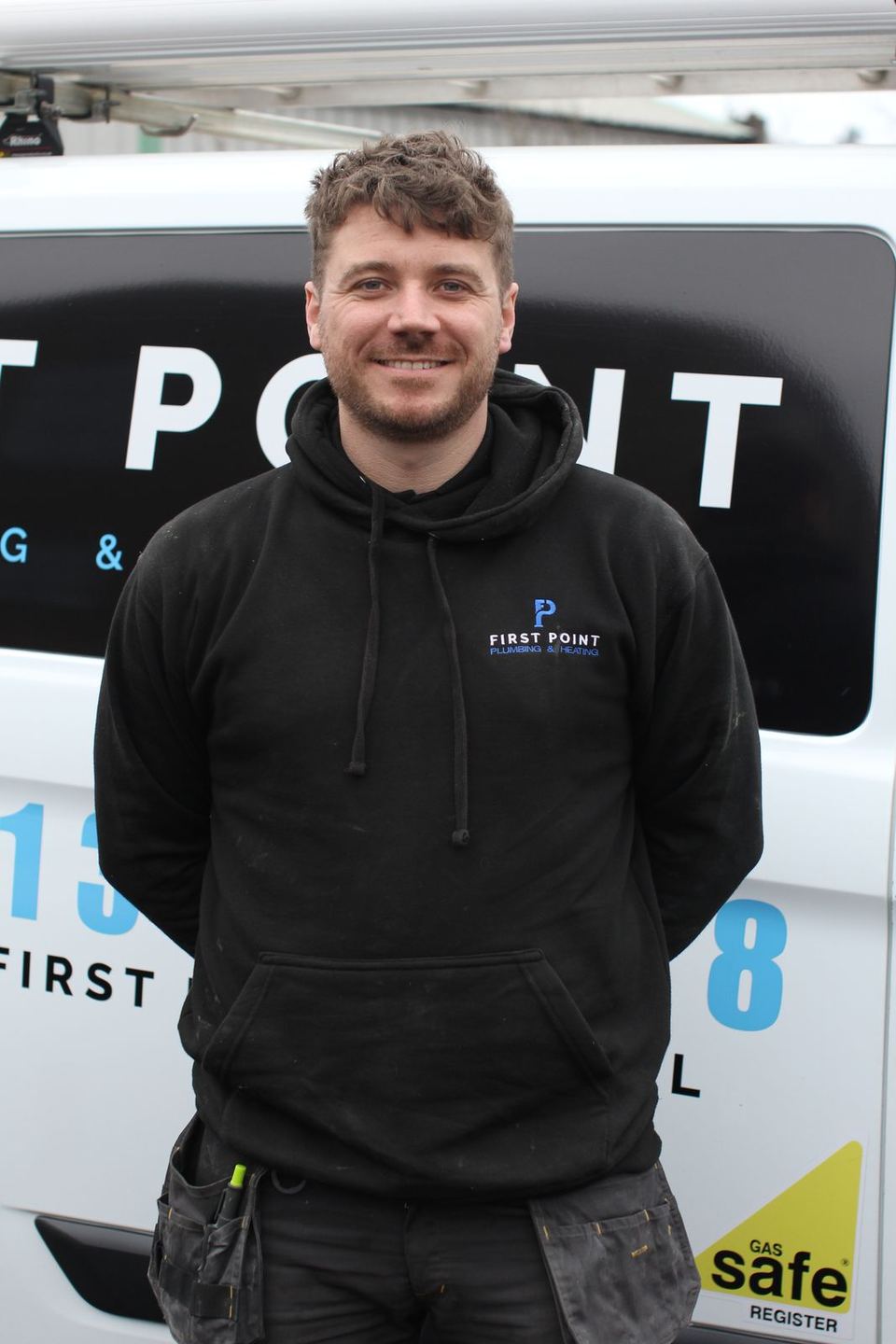 A First Point engineer in a black hoodie against the white van, the Gas Safe decal at the bottom right