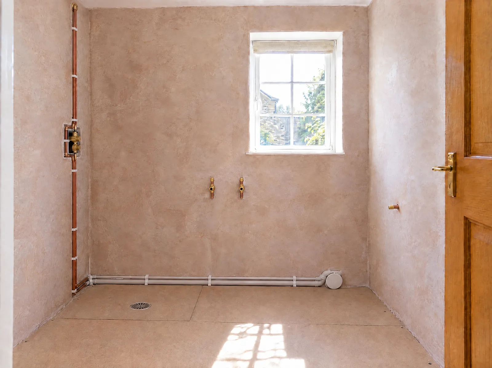 Illustration of first fix in the stripped bathroom: copper feeds to a concealed shower valve, a floor drain and the waste runs
